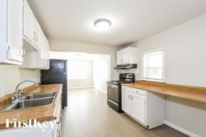 Saint Louis house for rent - a kitchen with white cabinets and white appliances and wood counter tops