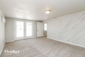 Tempe house for rent - A sparsely furnished room with a carpeted floor and a wooden wall.