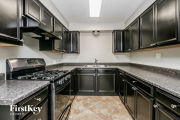 Tempe house for rent - A kitchen with black cabinets and a marble countertop.