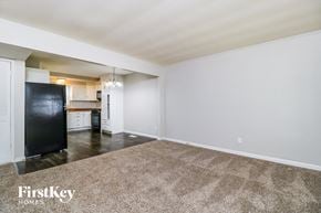 Florissant house for rent - A spacious room with a carpeted floor and a black refrigerator.