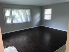 Matteson house for rent - an empty living room with wood floors and a window