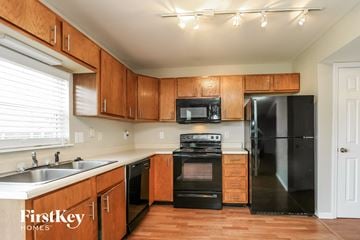 Avon house for rent - a kitchen with black appliances and wooden cabinets