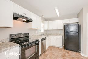 Conyers house for rent - a kitchen with white cabinets and stainless steel appliances