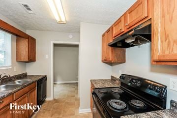 Jonesboro house for rent - a kitchen with wood cabinets and a stove and a sink