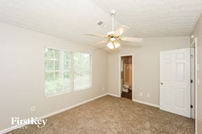 Jonesboro house for rent - a bedroom with a ceiling fan and a door to a bathroom