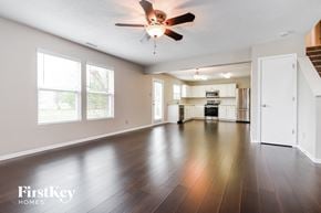 Greenfield house for rent - A spacious living room with a ceiling fan and hardwood floors.