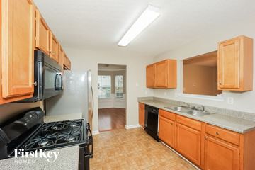 Hampton house for rent - A kitchen with wooden cabinets and a black stove top oven.