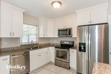 Fort Myers house for rent - A kitchen with a stainless steel refrigerator and a stove top oven.