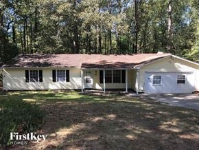 Stone Mountain house for rent - A white house with a brown roof is surrounded by trees.