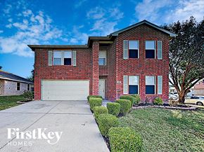 Arlington house for rent - A red brick house with a white garage door and a tree in front.