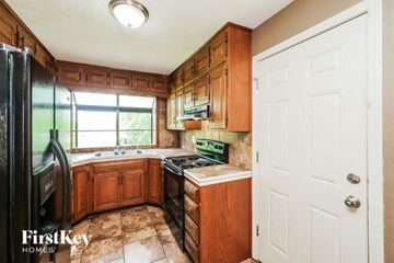 Raytown house for rent - A kitchen with wooden cabinets and a black refrigerator.