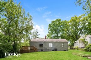 Raytown house for rent - A house with a brown roof and a porch is surrounded by green trees.