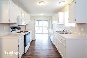 Peculiar house for rent - A kitchen with white cabinets and a stove top oven.