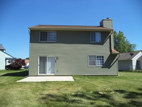Indianapolis house for rent - the back of a house with a lawn and a sidewalk