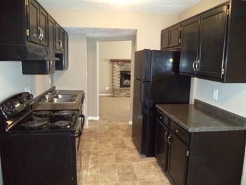 Indianapolis house for rent - a kitchen with black cabinets and a stove and a refrigerator