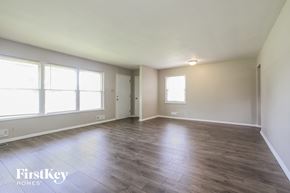 Indianapolis house for rent - A spacious room with wooden flooring and large windows.