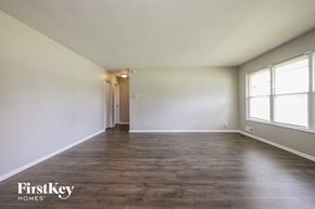 Indianapolis house for rent - A spacious room with wooden flooring and a door at the end.