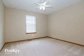 Lee's Summit house for rent - a bedroom with a white carpet and a ceiling fan
