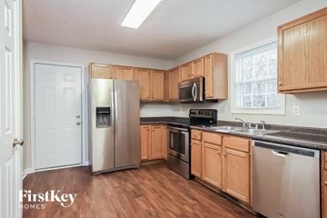 Knightdale house for rent - a kitchen with wooden cabinets and stainless steel appliances