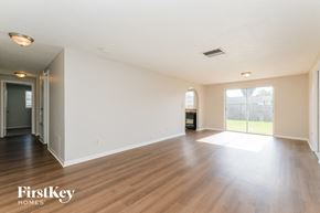 Tarpon Springs house for rent - A spacious empty room with wooden flooring and white walls.