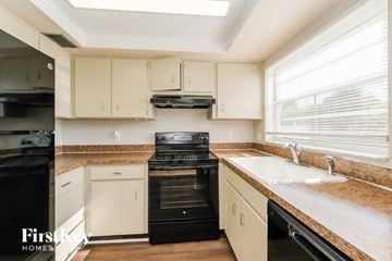 Tarpon Springs house for rent - A kitchen with black appliances and white cabinets.