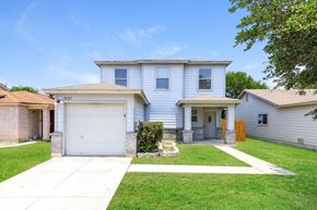 San Antonio house for rent - A two-story house with a garage is surrounded by a well-kept lawn.