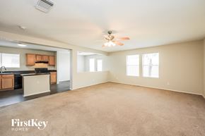 San Antonio house for rent - A spacious living room with a kitchen area in the background and a carpeted floor.