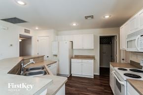 Cape Coral house for rent - a kitchen with white cabinets and white appliances and white counter tops