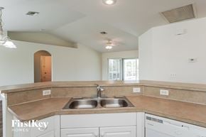 Cape Coral house for rent - a kitchen with white cabinets and a sink and a window