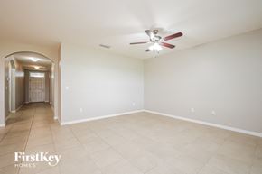 Cape Coral house for rent - A spacious room with a fan and a doorway leading to another room.