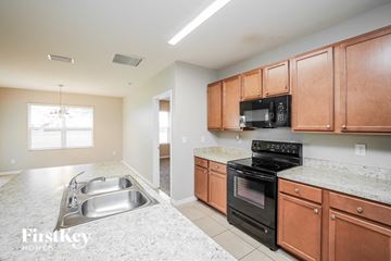 Cape Coral house for rent - A kitchen with a black microwave and stove top oven.