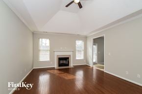 Calera house for rent - A spacious room with a fireplace and a ceiling fan.