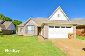 Cordova house for rent - a brick house with a white garage door and a green lawn