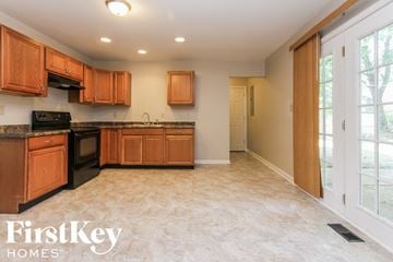 Indianapolis house for rent - a kitchen with wooden cabinets and black appliances and a window