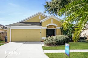 Riverview house for rent - a yellow house with a garage door and palm tree
