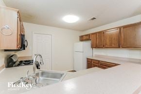 Dallas house for rent - a kitchen with white appliances and wooden cabinets and a sink