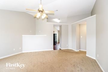 Cordova house for rent - a spacious living room with carpet and a ceiling fan