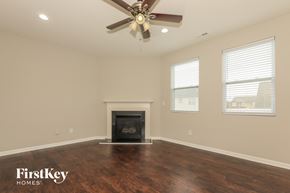 Indian Trail house for rent - A room with a fireplace and a ceiling fan.