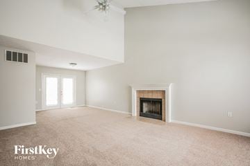 Indianapolis house for rent - A spacious living room with a fireplace and a ceiling fan.