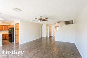 Buckeye house for rent - A spacious empty room with a ceiling fan and a kitchen area in the background.