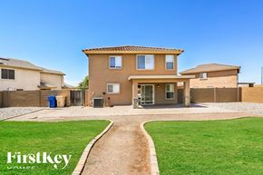 Buckeye house for rent - A house with a brown roof and tan walls is surrounded by a gravel driveway and a grassy lawn.