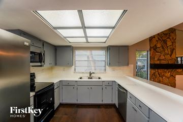 Plant City house for rent - a kitchen with white cabinets and a sink and a window