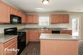 Mcdonough house for rent - a kitchen with wooden cabinets and black appliances and granite counter tops