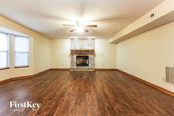 Bargersville house for rent - a living room with a fireplace and wooden floors and a ceiling fan