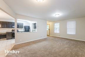 Aurora house for rent - an empty living room with a kitchen in the background