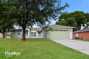 Poinciana house for rent - a white house with a lawn and trees