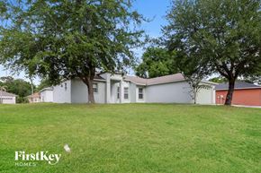 Poinciana house for rent - a white house with trees in the grass