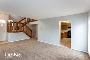 Indianapolis house for rent - A spacious room with a carpeted floor and a wooden staircase.