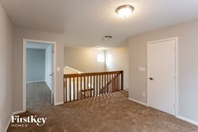 Indianapolis house for rent - A carpeted room with a wooden railing and two doors.