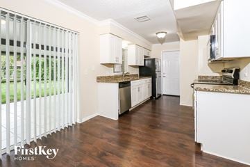 West Palm Beach house for rent - a kitchen with white cabinets and a black refrigerator